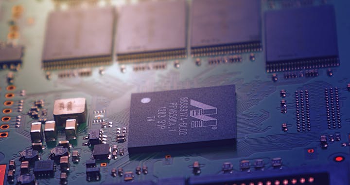 Detailed image of an electronic circuit board showing microchips and intricate wiring in a modern technological setting.